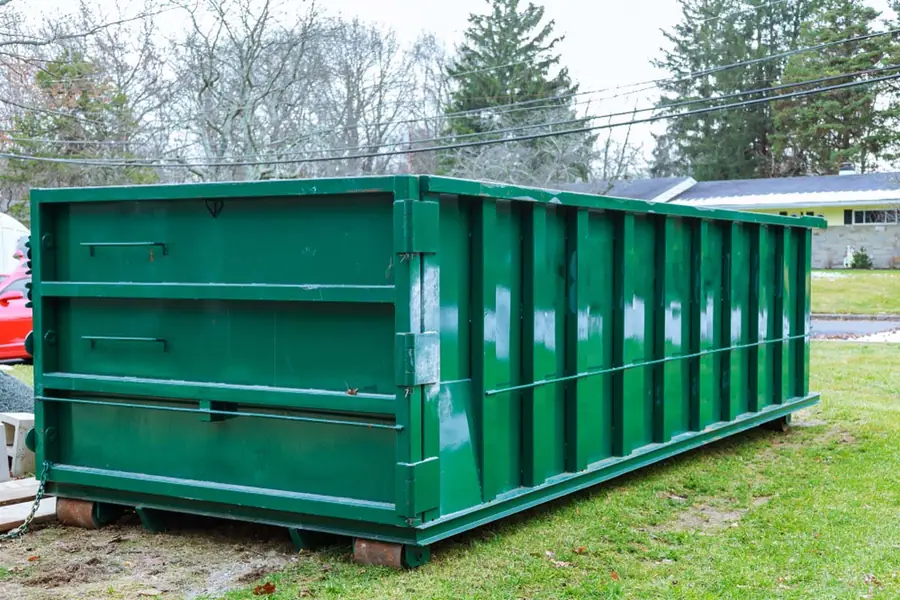 Large roll-off dumpster on wooden runners for a yard cleanup