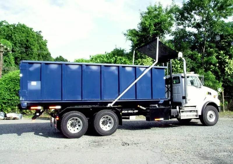 Roll-off truck carrying a dumpster for delivery