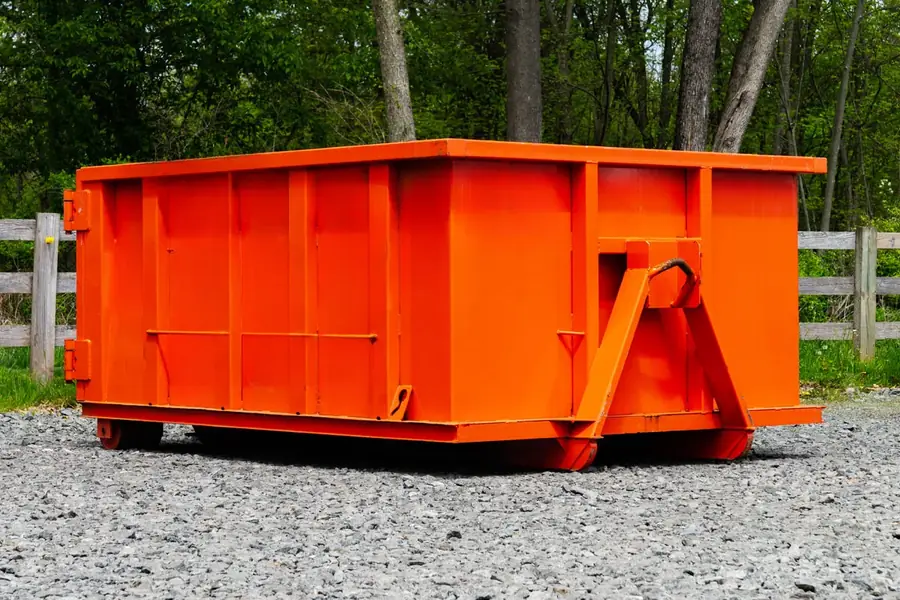 Low-wall roll-off dumpster for heavy debris on a gravel pad